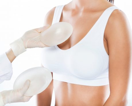 Female doctor choosing mammary prosthesis with her patient over Portrait of female doctor choosing mammary prosthesis with her patient over white background.